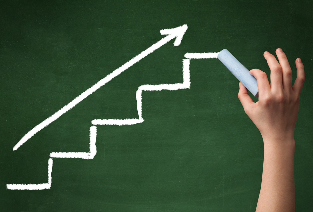 Stairs heading upwards with an arrow drawn by hand on a green chalkboard.